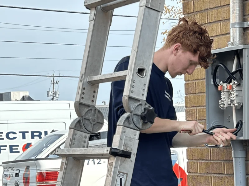 A licensed Burlington electrician repairing an outdoor electrical panel, ensuring safe and efficient power distribution for a commercial property.