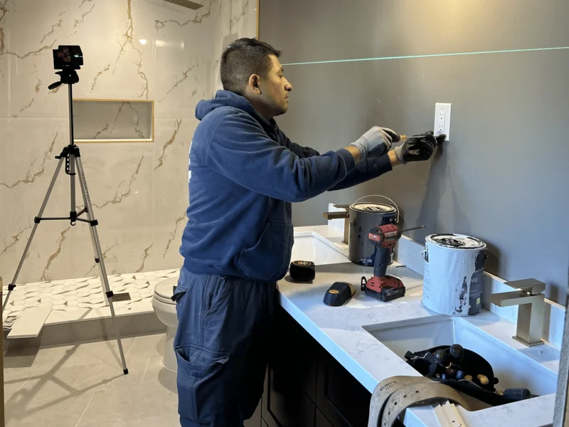 A local electrician in Burlington installing a new power outlet in a modern residential bathroom, ensuring code-compliant electrical safety and functionality.