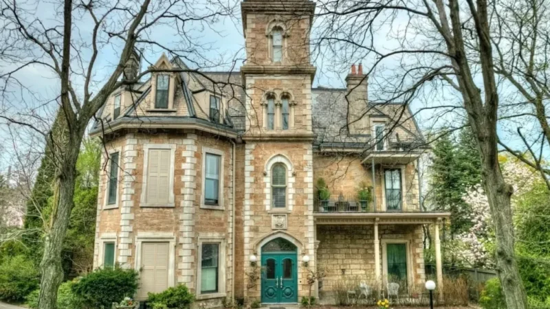 The historic Ballinahinch estate at 316 James Street South in Hamilton, Ontario, showcasing its 1850s stone architecture with a teal Gothic doorway, ornate marble mantle, and a private patio. This vintage condominium complex, renowned for its grand 12-foot ceilings and hardwood floors, captures the essence of Hamilton's architectural heritage.